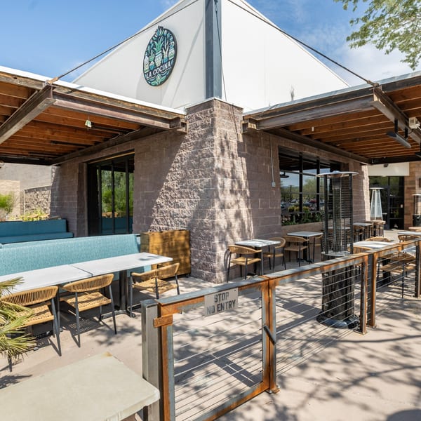 La Cocina restaurant exterior with a patio featuring tables, chairs, and a turquoise bench.