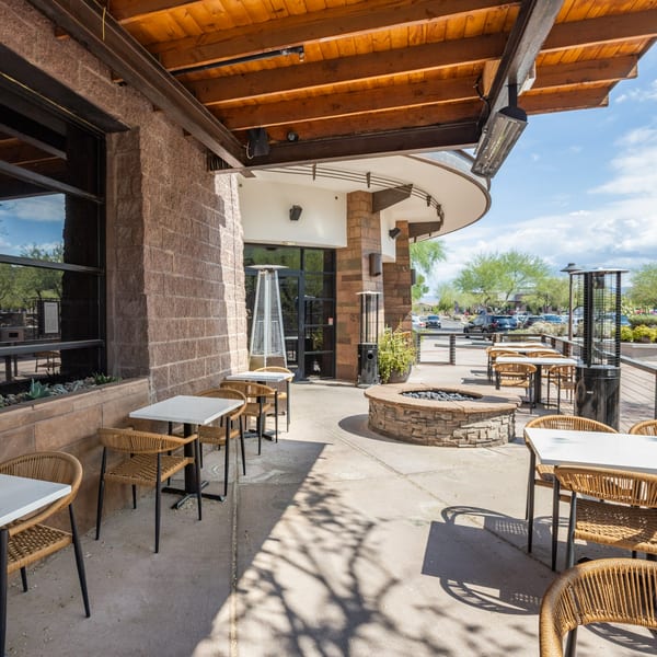 La Cocina's outdoor patio features wicker chairs, white tables, a stone fire pit, and heaters.