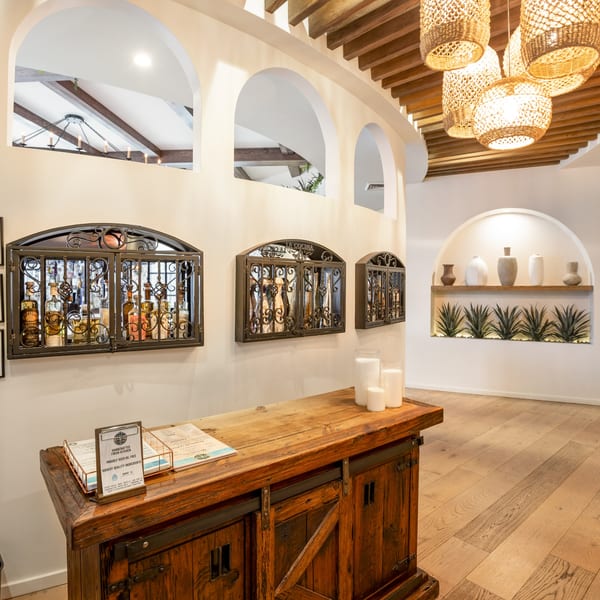 La Cocina's interior features a rustic wooden counter, arched wall niches, and decorative tequila displays.